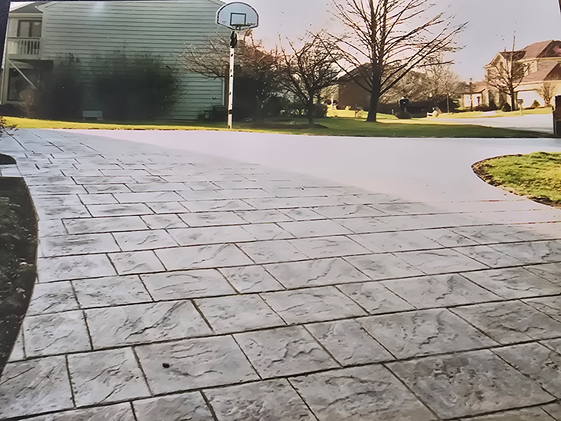 A man in yellow boots is cleaning a brick walkway in a garden.