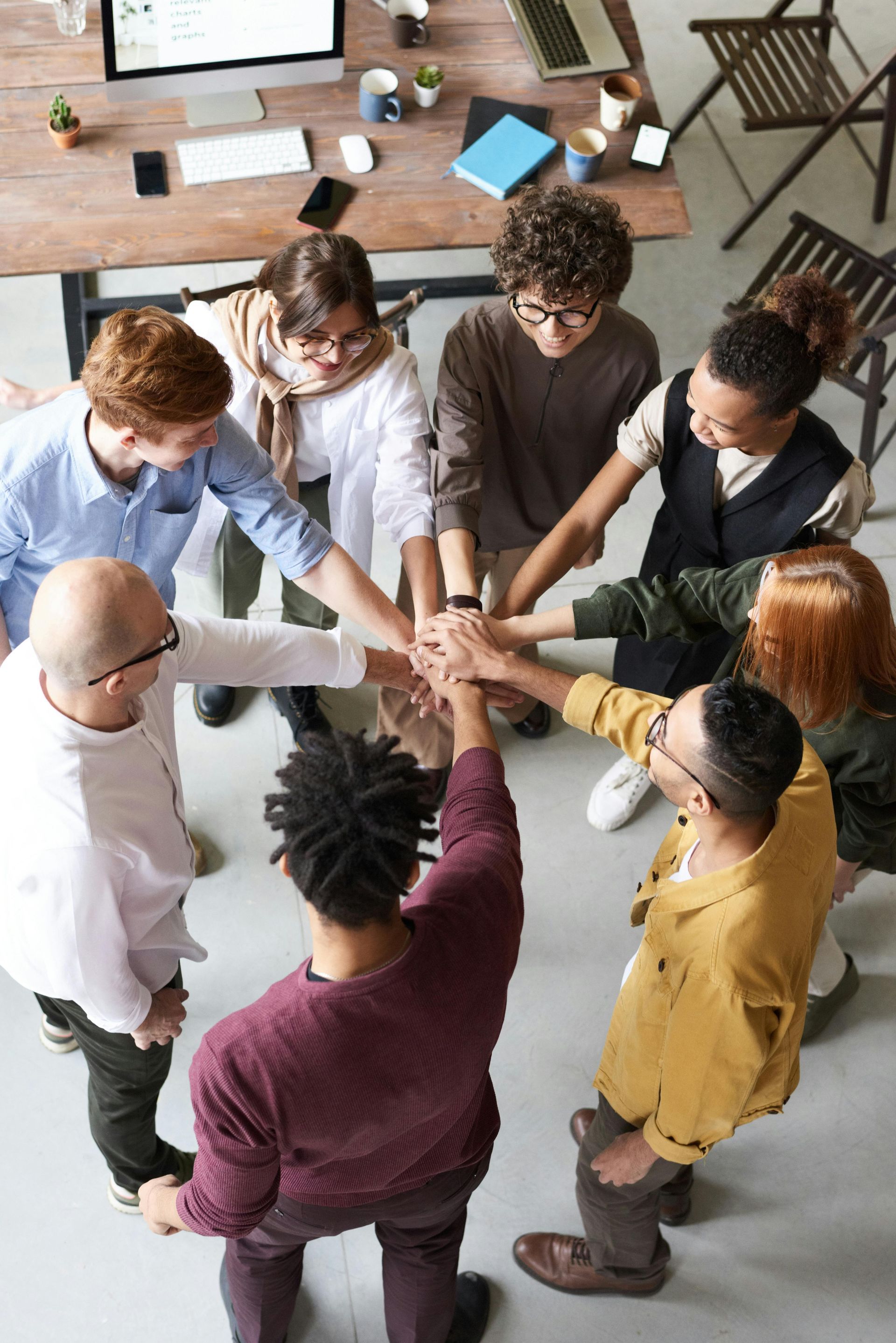 Groupe de personnes se tenant par la main en cercle, debout autour d'une table dans un bureau.