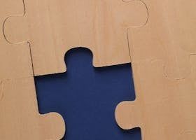 Pièces de puzzle en bois clair, une manquante, révélant un espace bleu.