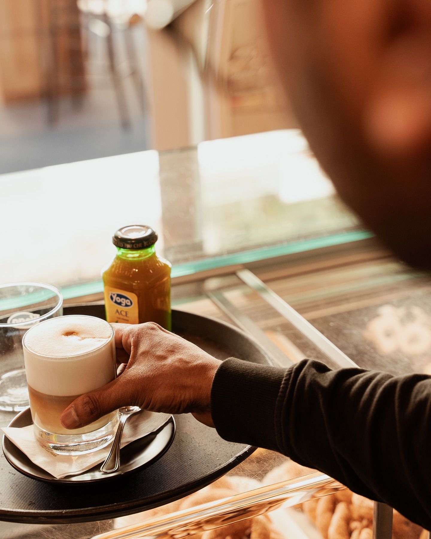 Persona che tiene un vassoio con una bottiglia di latte e succo vicino alla finestra di un bar.
