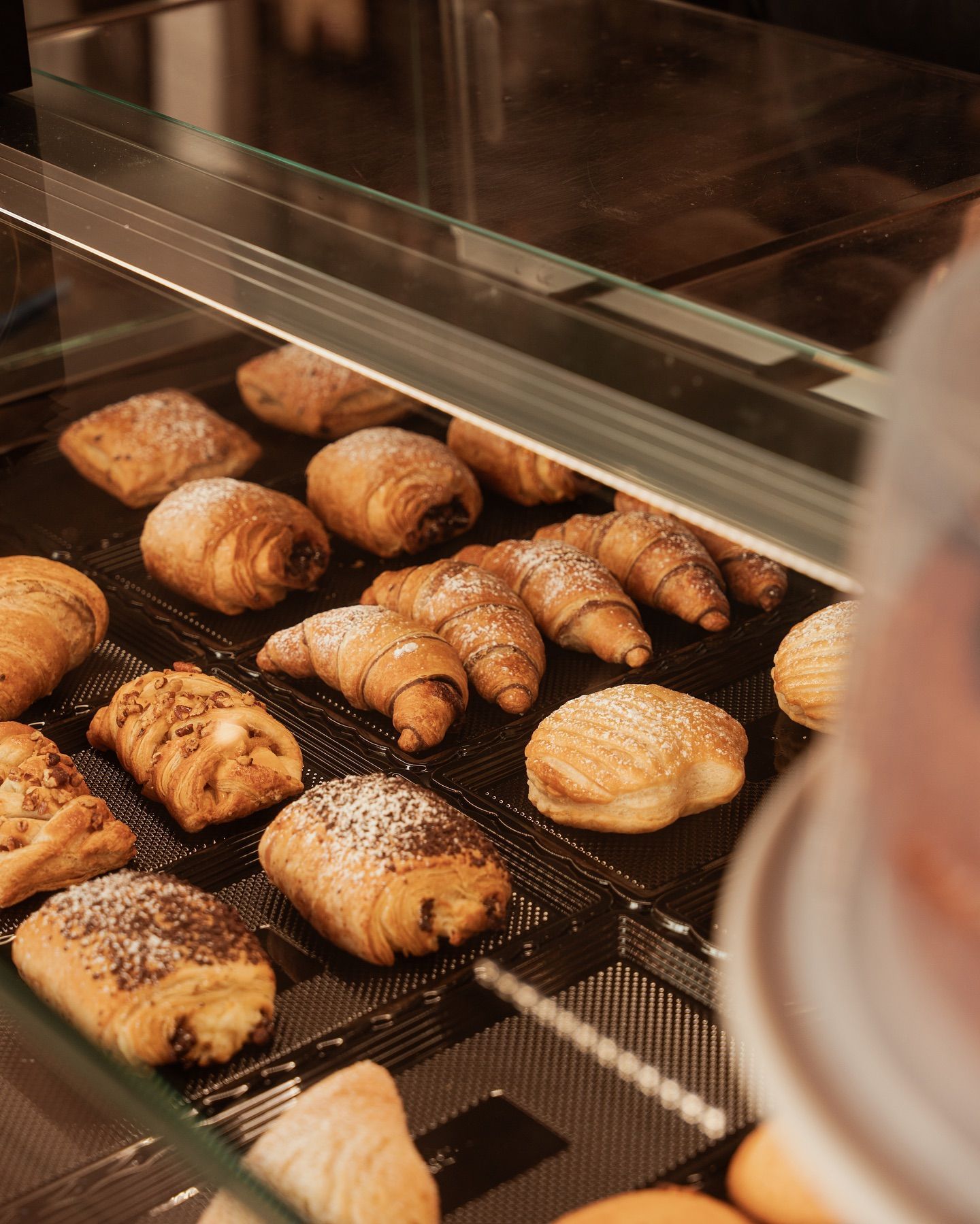 Pasticcini esposti in una vetrina da panetteria, tra cui croissant e panini dolci.