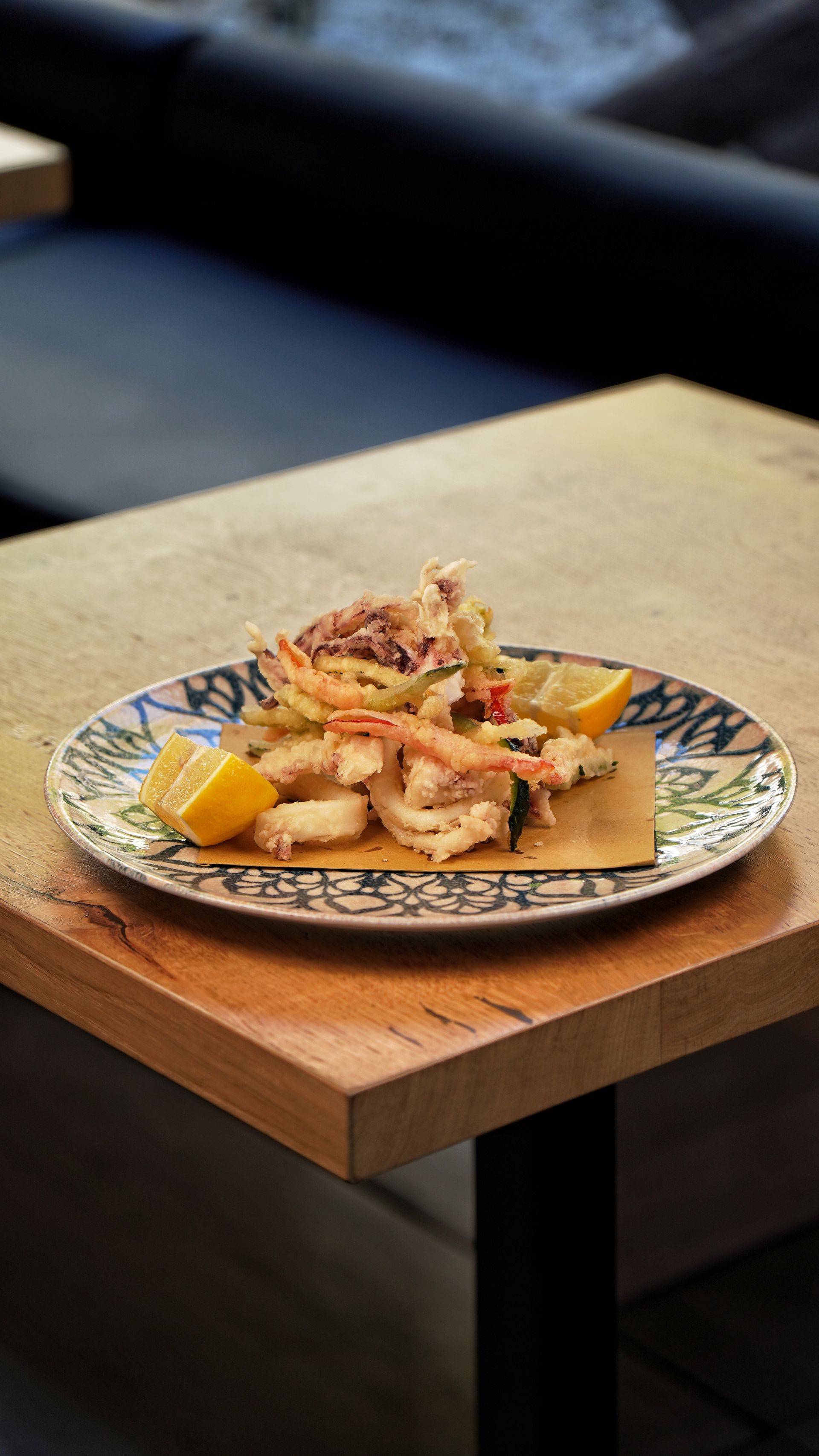 Piatto di frutti di mare fritti con spicchi di limone su un tavolo di legno.