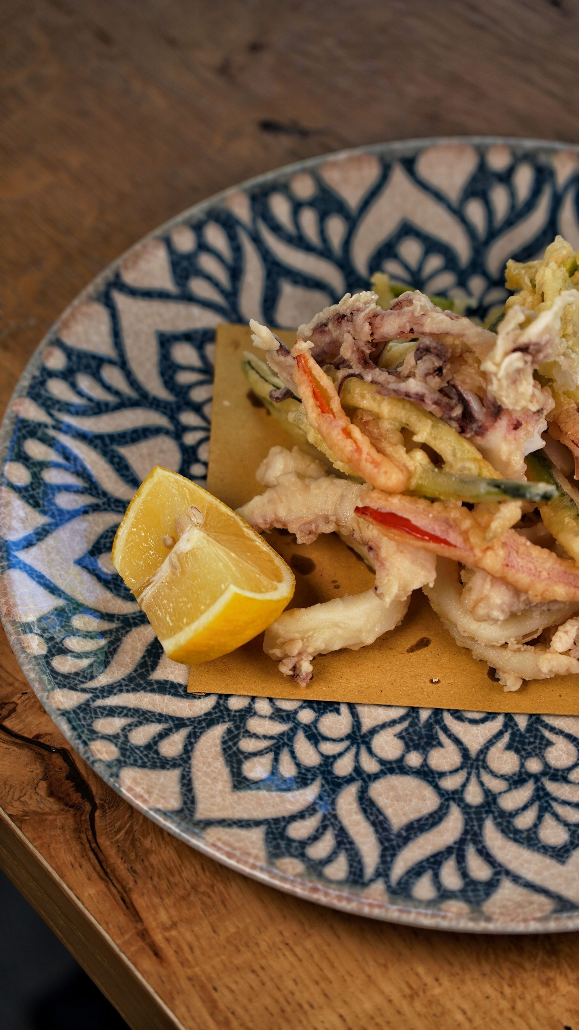 Piatto di pesce e verdure fritte con spicchio di limone.