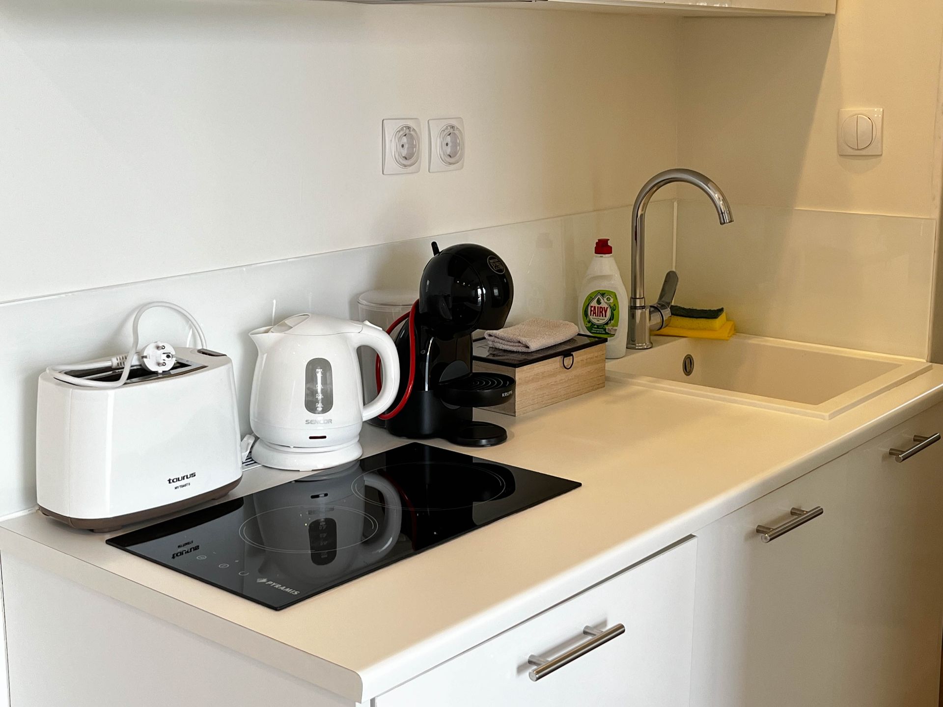 Small kitchen with white cabinets, countertop, and appliances like a toaster, kettle, and coffee maker.