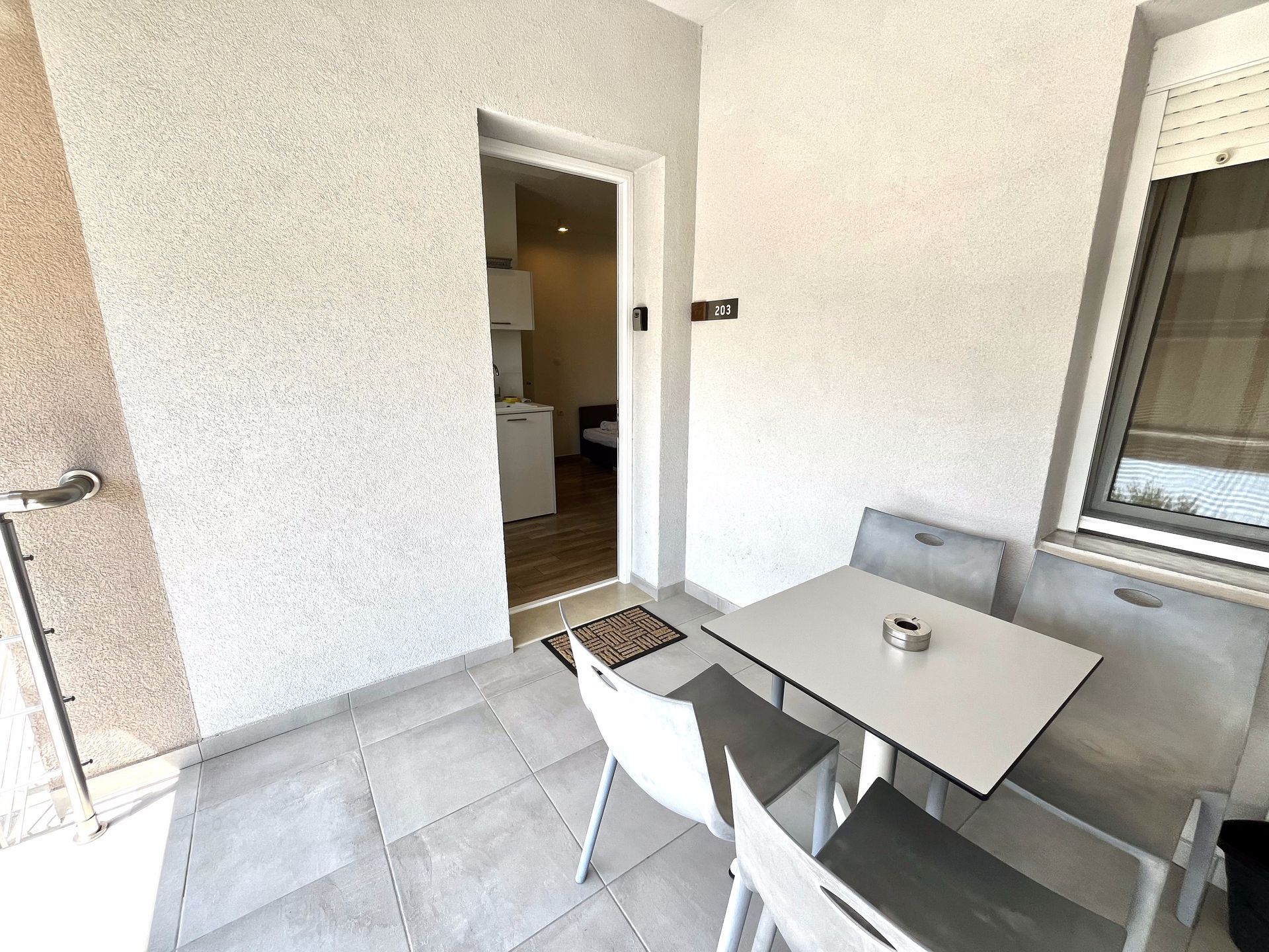 Balcony with table and chairs. Doorway leads to interior with appliances.