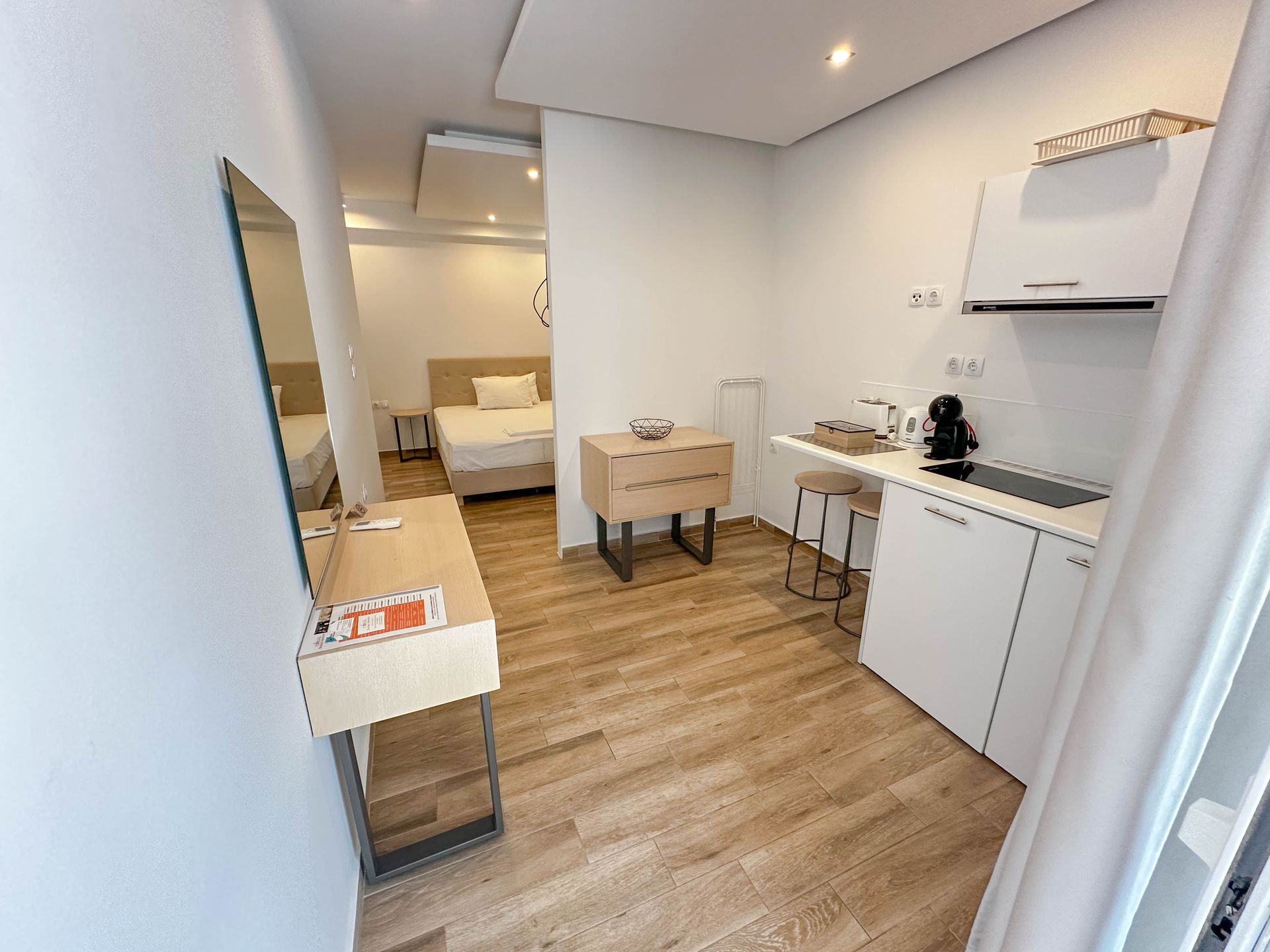 Small modern studio apartment with kitchenette, bed, and desk.
