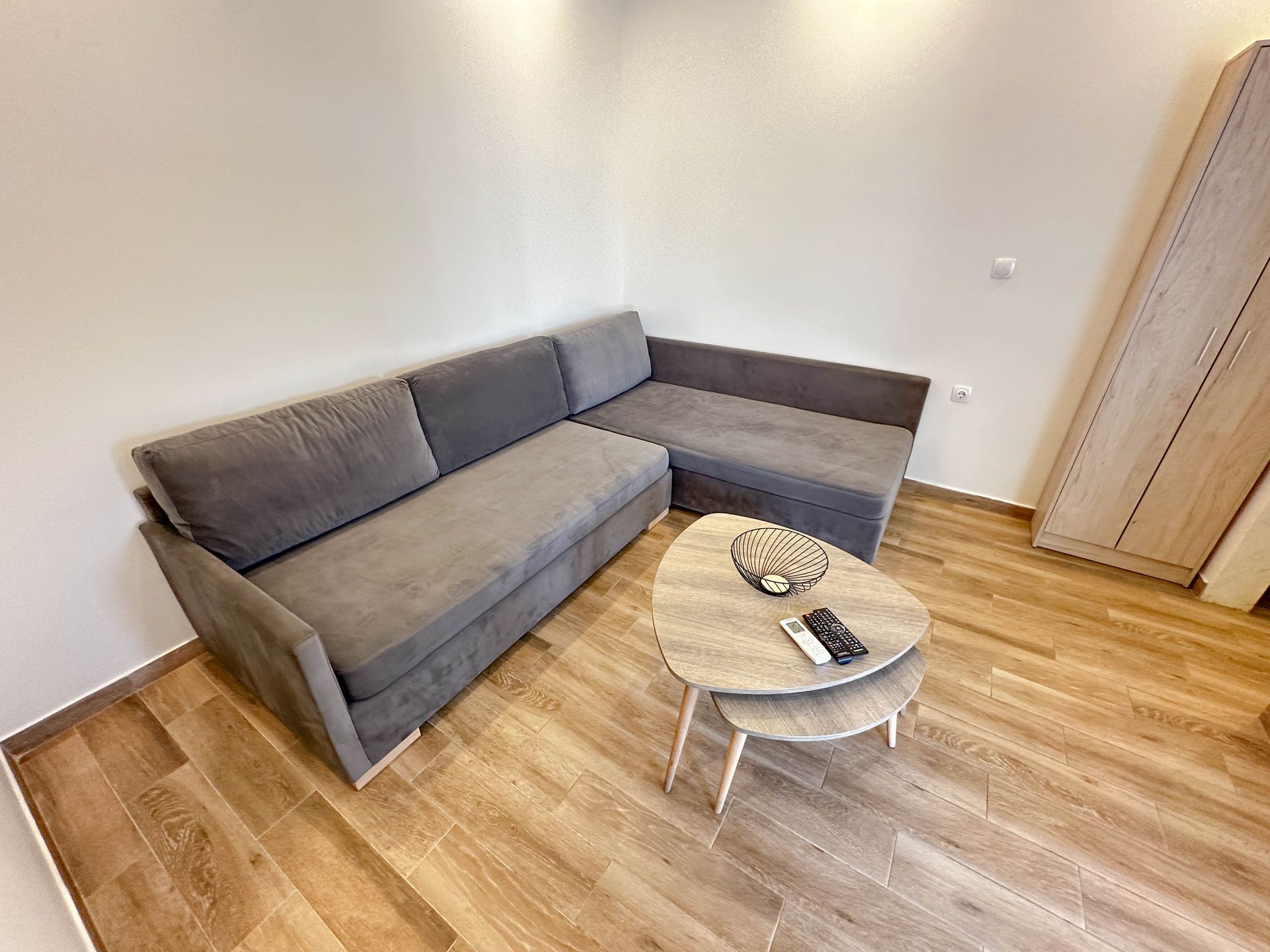 Cozy living room with a gray sectional sofa, two-tiered coffee table, and light wood flooring.