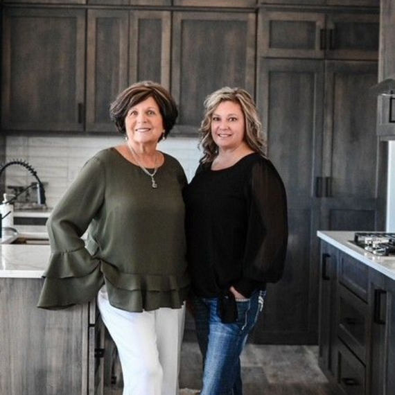 A man and a woman are sitting on a dock overlooking a lake.