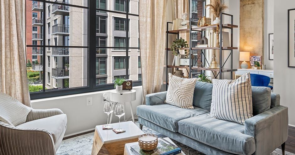 Spacious living room with sofa, coffee table, bookshelf, and oversized windows at The Foundry.