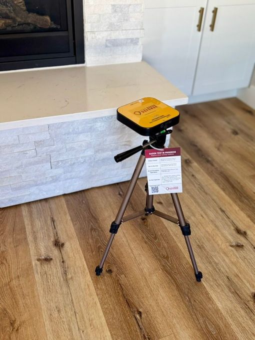 Yellow device mounted on a tripod in a kitchen with light wood floors and white cabinets