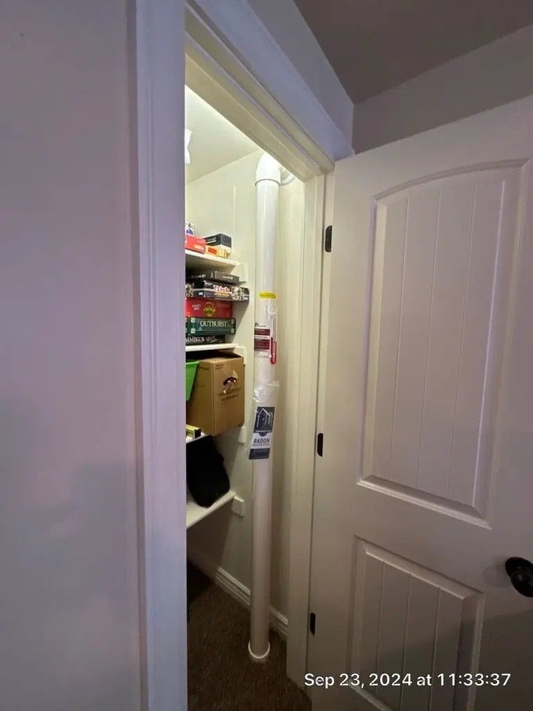 Open closet door revealing shelves, bins, and hanging clothes in a narrow hallway.