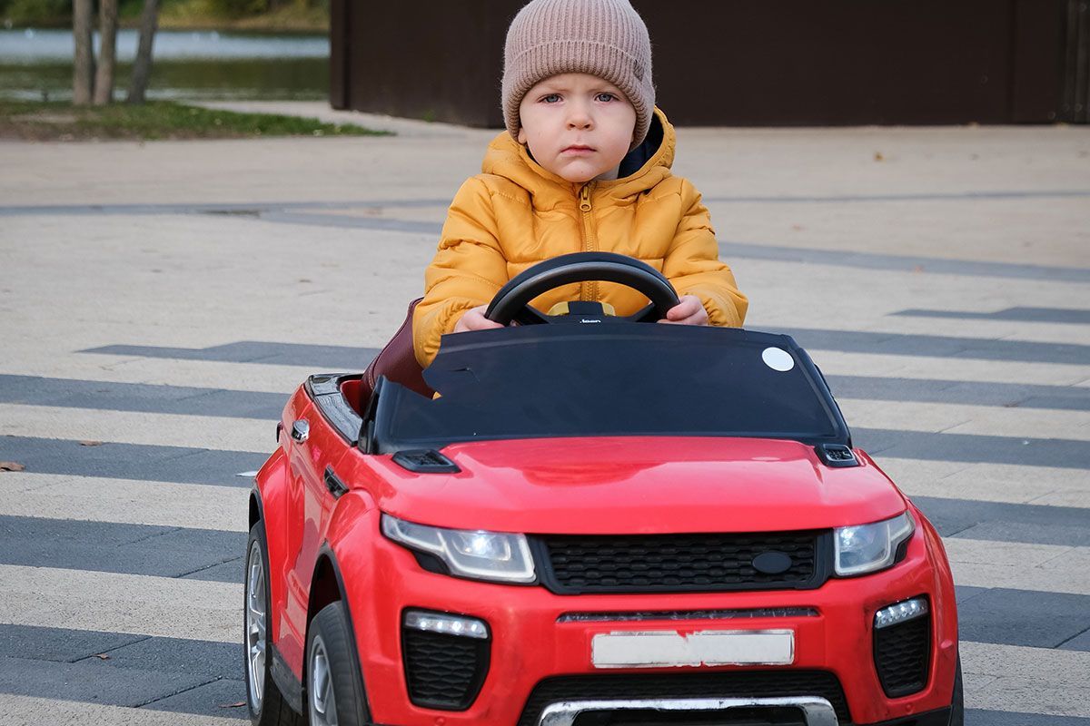 Little boy driving a red car