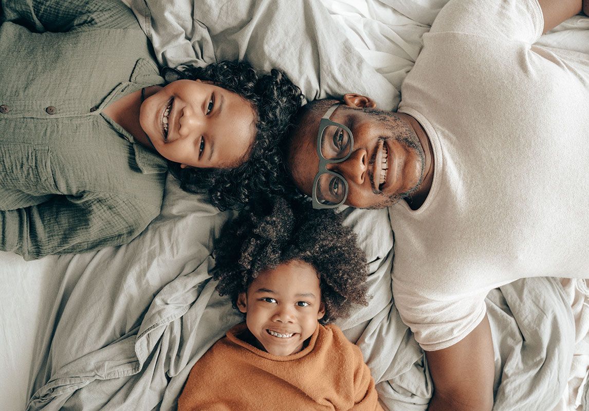 A man and two children are laying on a bed.