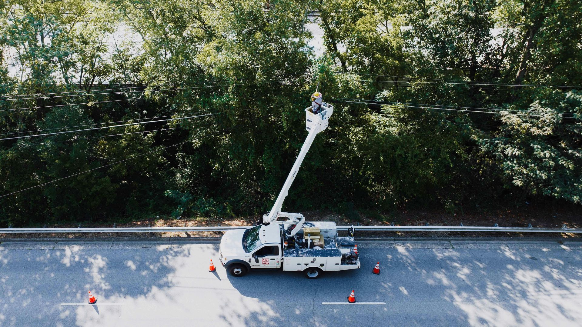 A curved, dark grey landscape border surrounds mulch and pink flowers at the base of a post in a grassy yard.