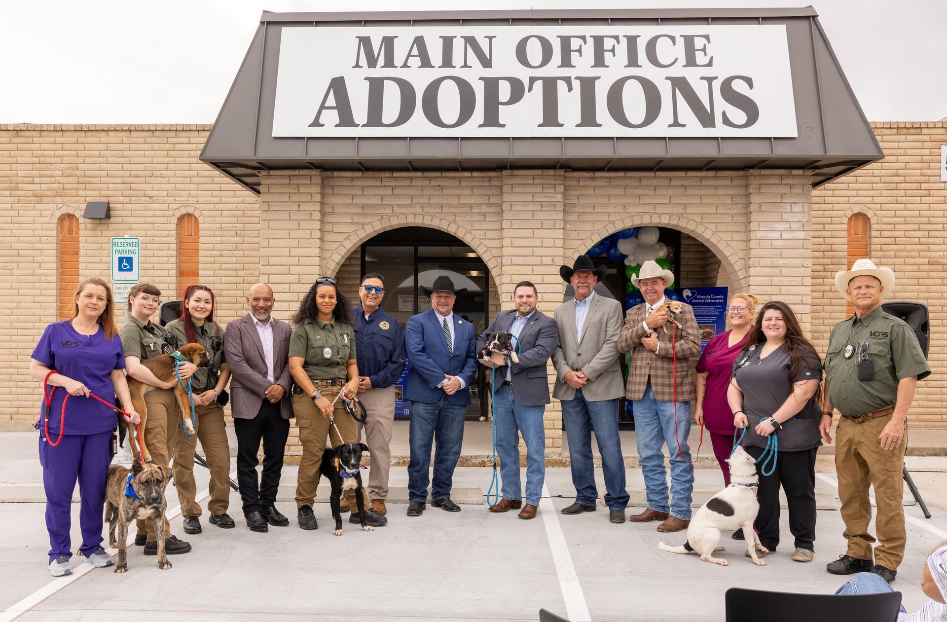 People and dogs stand outside an adoption center, 