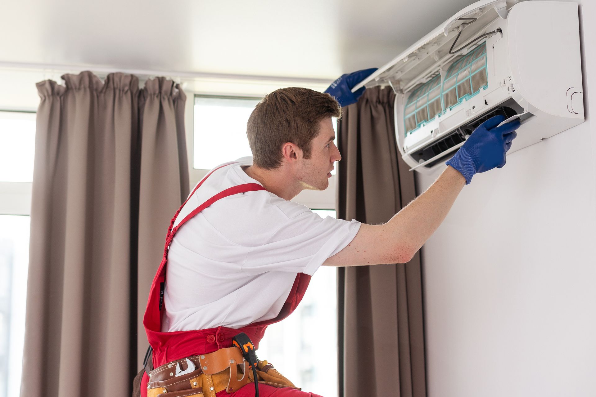 Electrician repairing an air conditioner unit during routine air conditioning maintenance service.