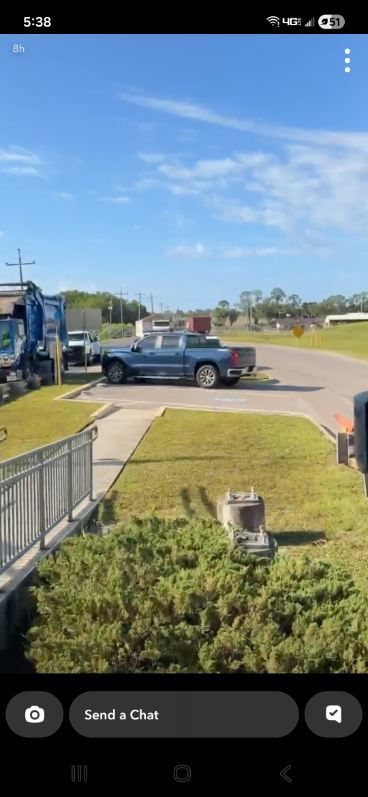 Tow truck loading a pickup truck on a suburban street under a clear blue sky