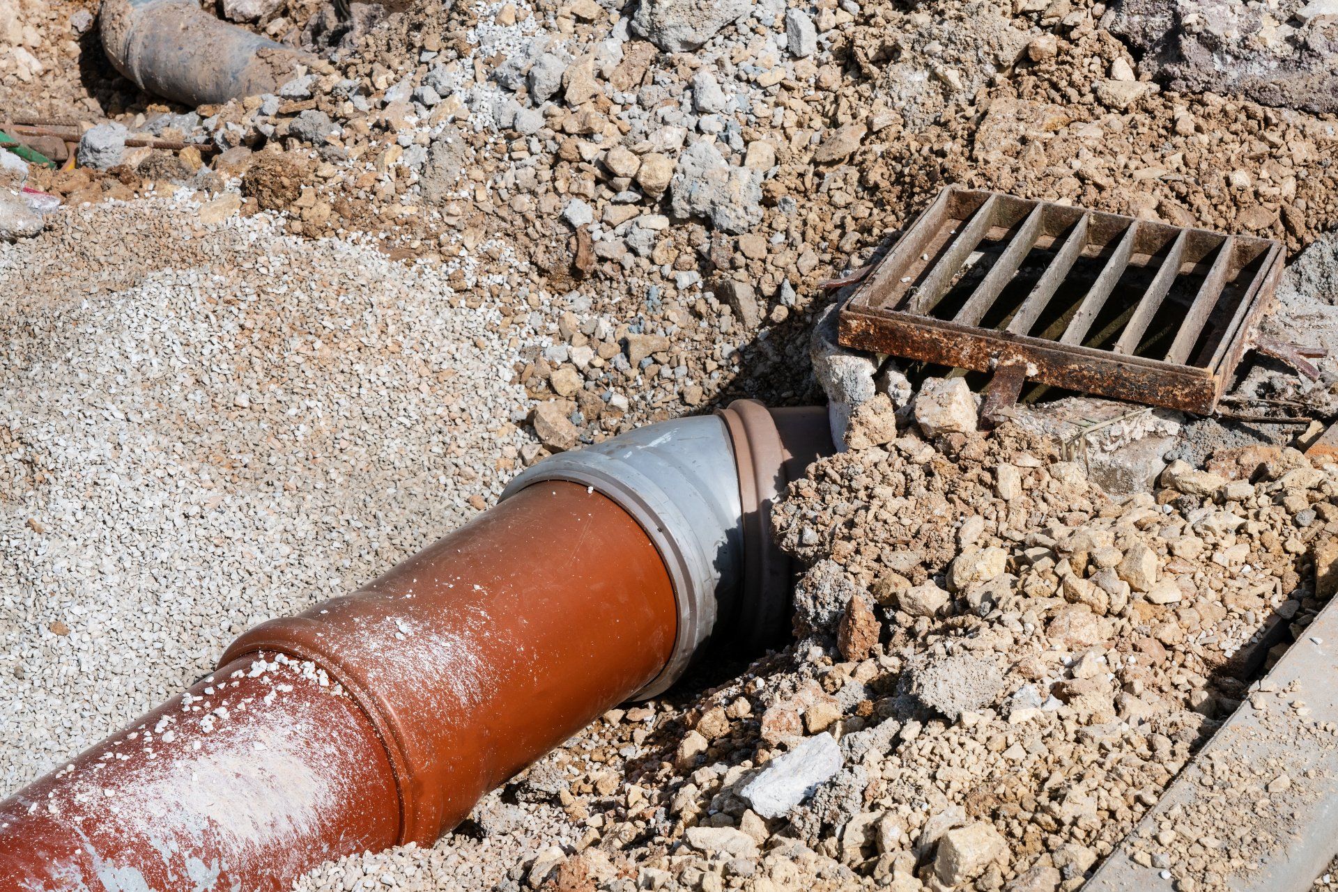 Construction workers laying underground storm sewers, water main, sanitary sewer, and drain systems at a construction site.