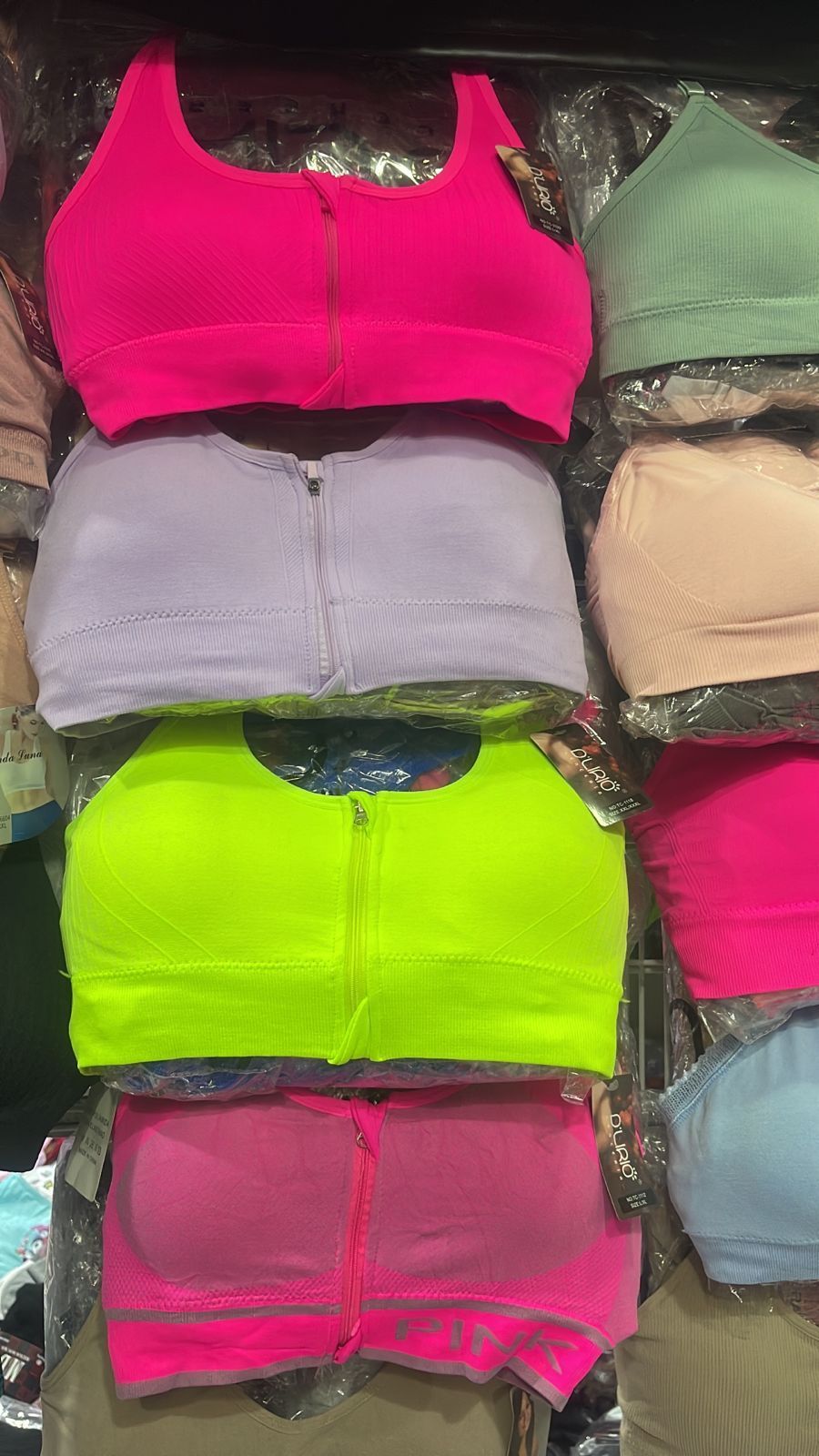 Filas de coloridos sujetadores deportivos con cremallera en envases de plástico.