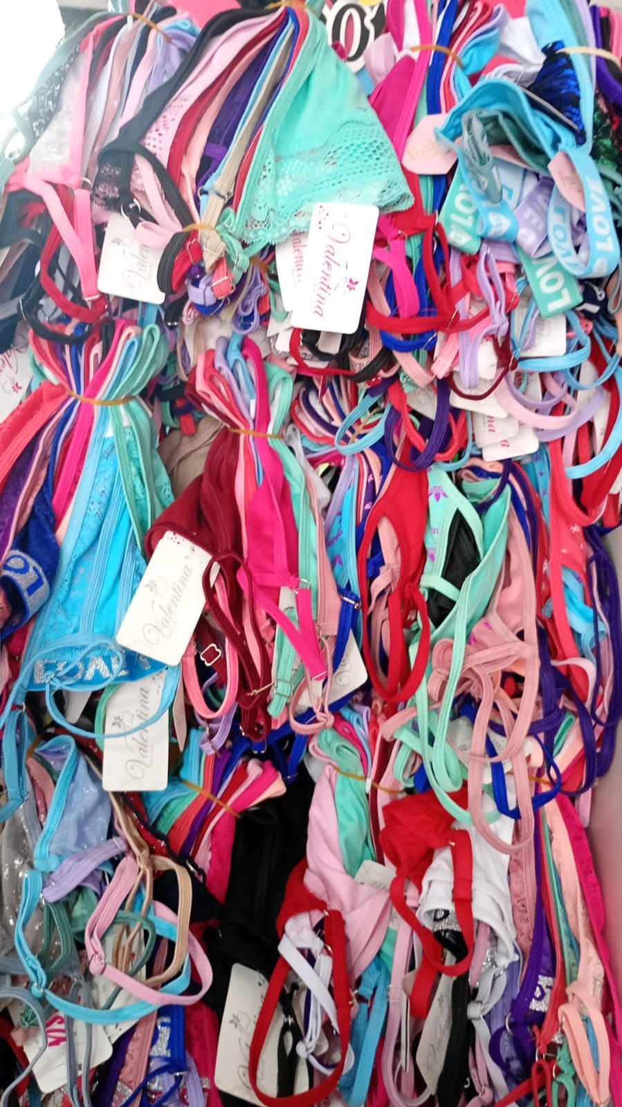 Montón de coloridos bañadores a la venta, expuestos en un perchero.