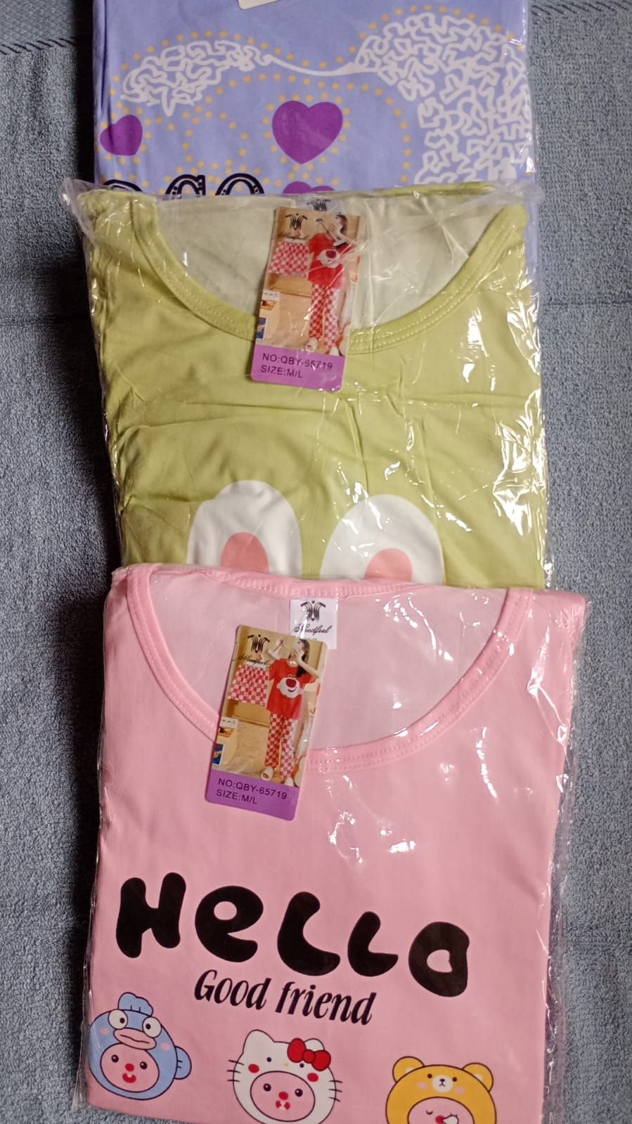 Pijamas apiladas y empaquetadas en tonos lavanda, verde y rosa, con estampados gráficos y etiquetas.