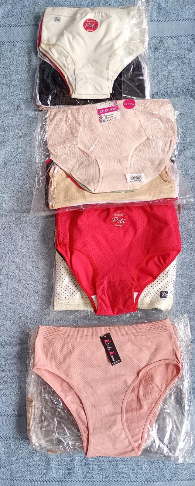 Cinco pares de ropa interior empaquetada en colores crema, rosa y rojo, dispuestos verticalmente sobre una superficie azul.