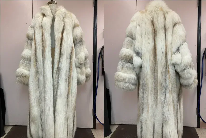 Full-length, fluffy, light-colored fur coat on a dress form. Vertical striped pattern with wide sleeves.