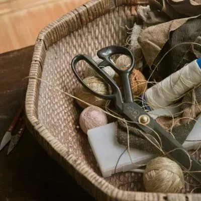 Basket of sewing tools, including scissors, thread spools, and fabric scraps.