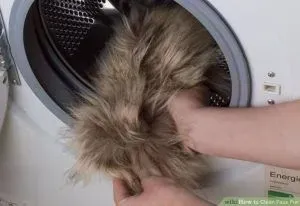 A person puts a fluffy brown faux fur item into a washing machine.