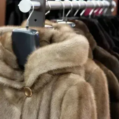 Fur coats hanging on a rack, close-up shot of the soft, brown material.