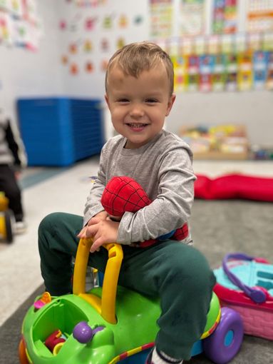 A little boy is sitting at a table holding a red toy dinosaur - Dyer, IN - Bright Beginner's Academy
