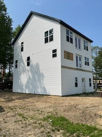 A large white house with a lot of windows is sitting on top of a dirt field.