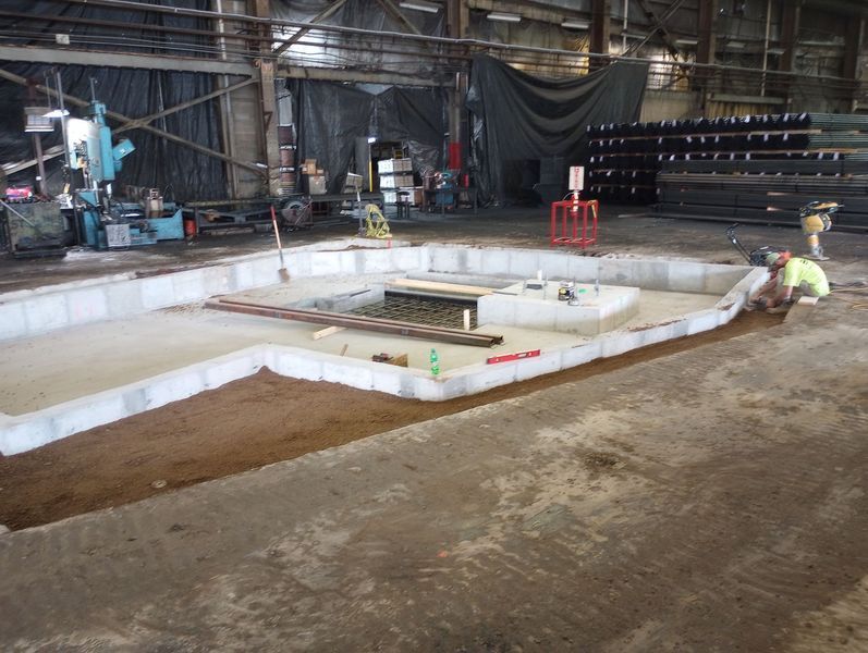 A man is working on a concrete floor in a factory.
