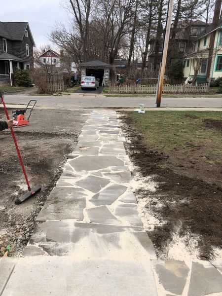 A stone walkway is being built in front of a house.