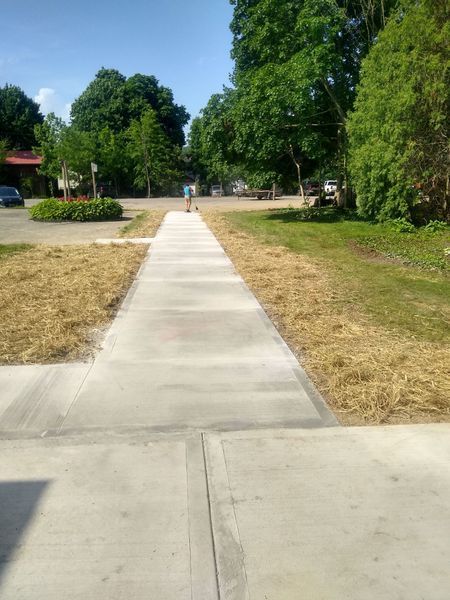 A concrete walkway going through a grassy field