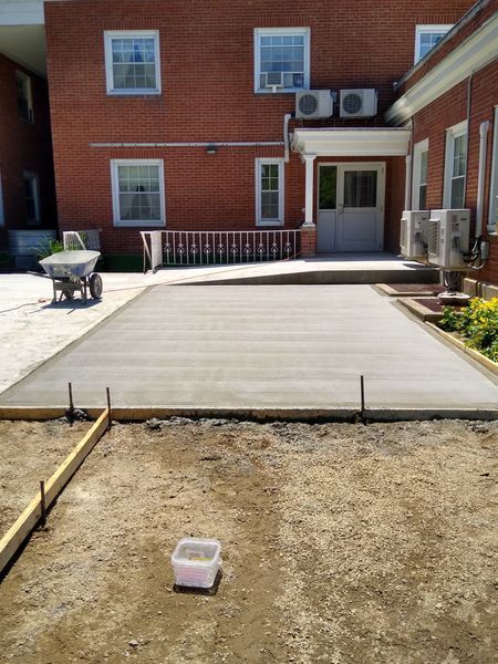 A concrete driveway is being built in front of a brick building