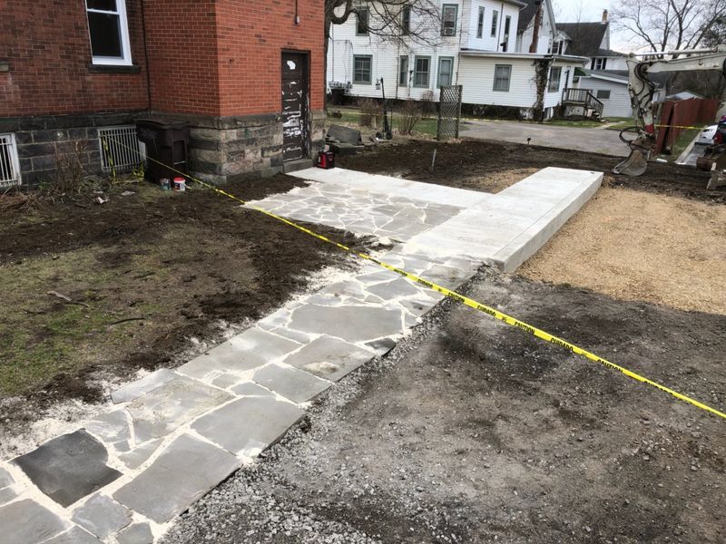 A stone walkway is being built in front of a brick building.