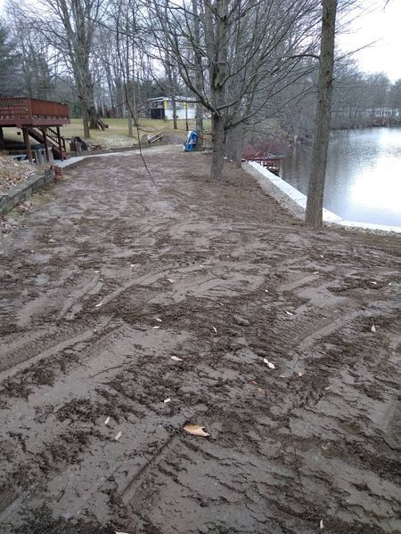 A dirt road leading to a lake with trees in the background.