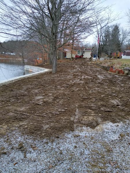 A dirt road leading to a house with a tree in the background.