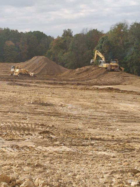 A construction site with a lot of dirt and trees in the background