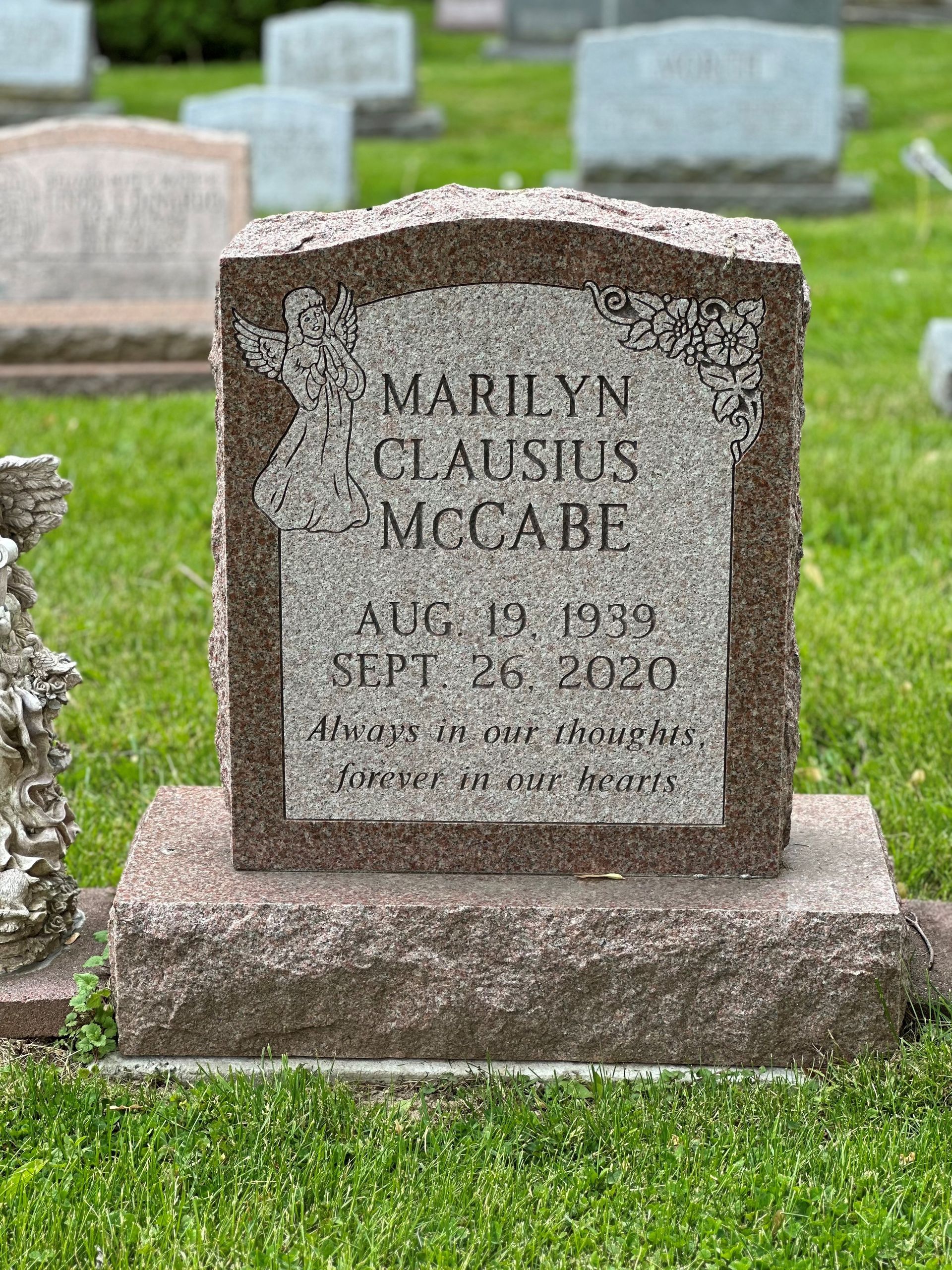 A gravestone for marilyn clausius mccabe is in a cemetery.