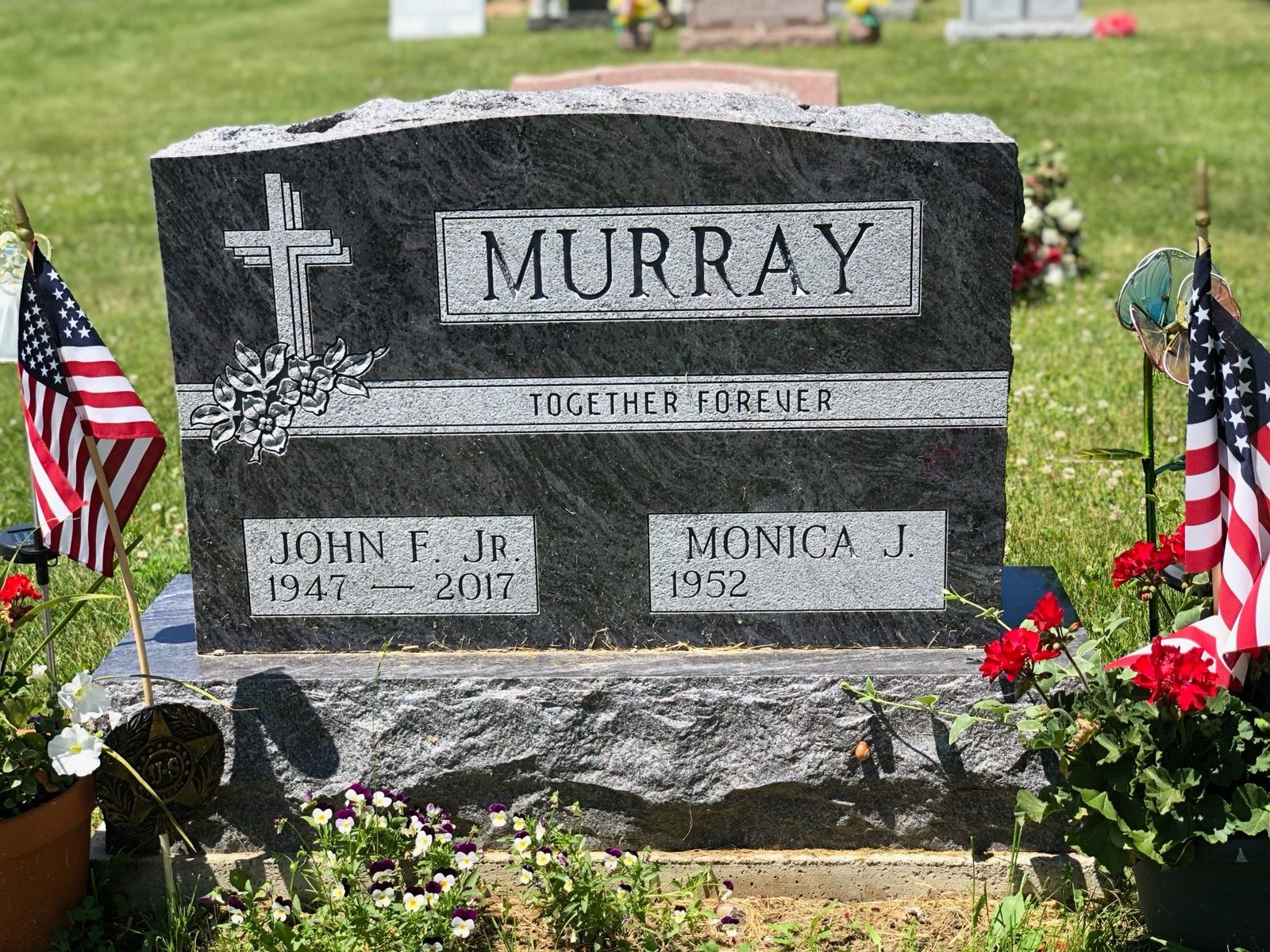 Grave of John and Monica Murray, black granite with a cross and American flags.