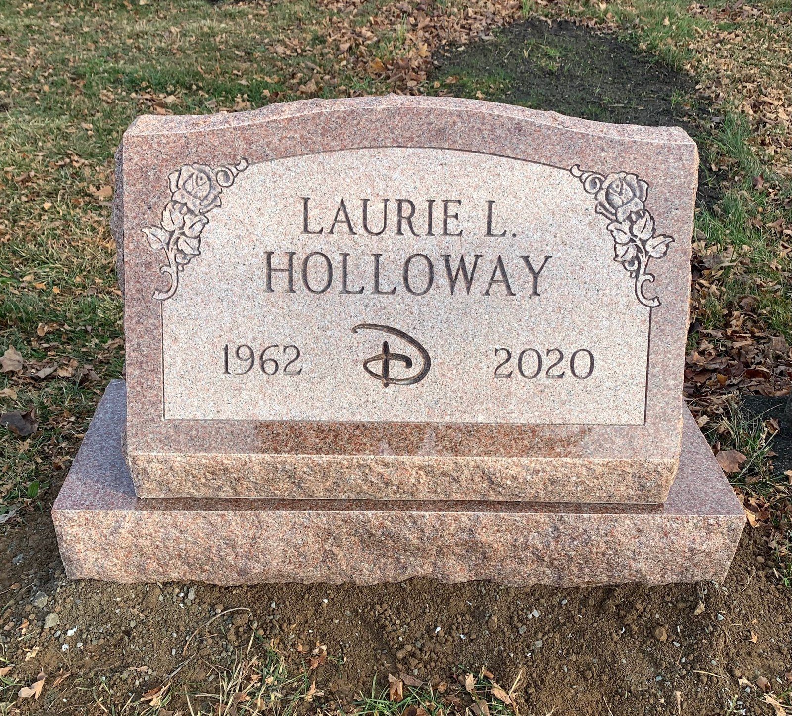 Headstone for Laurie L. Holloway, featuring Disney logo, with birth year 1962 and death year 2020. Pink granite, set outside.