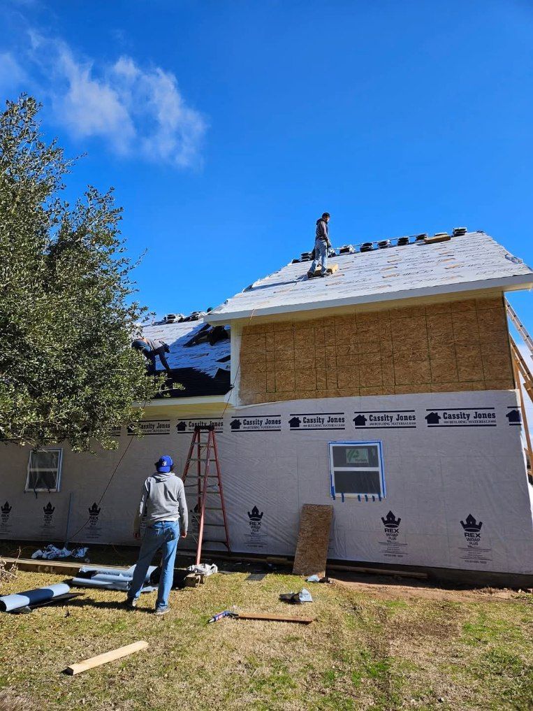A brick house with a gray roof and a blue sky in the background.