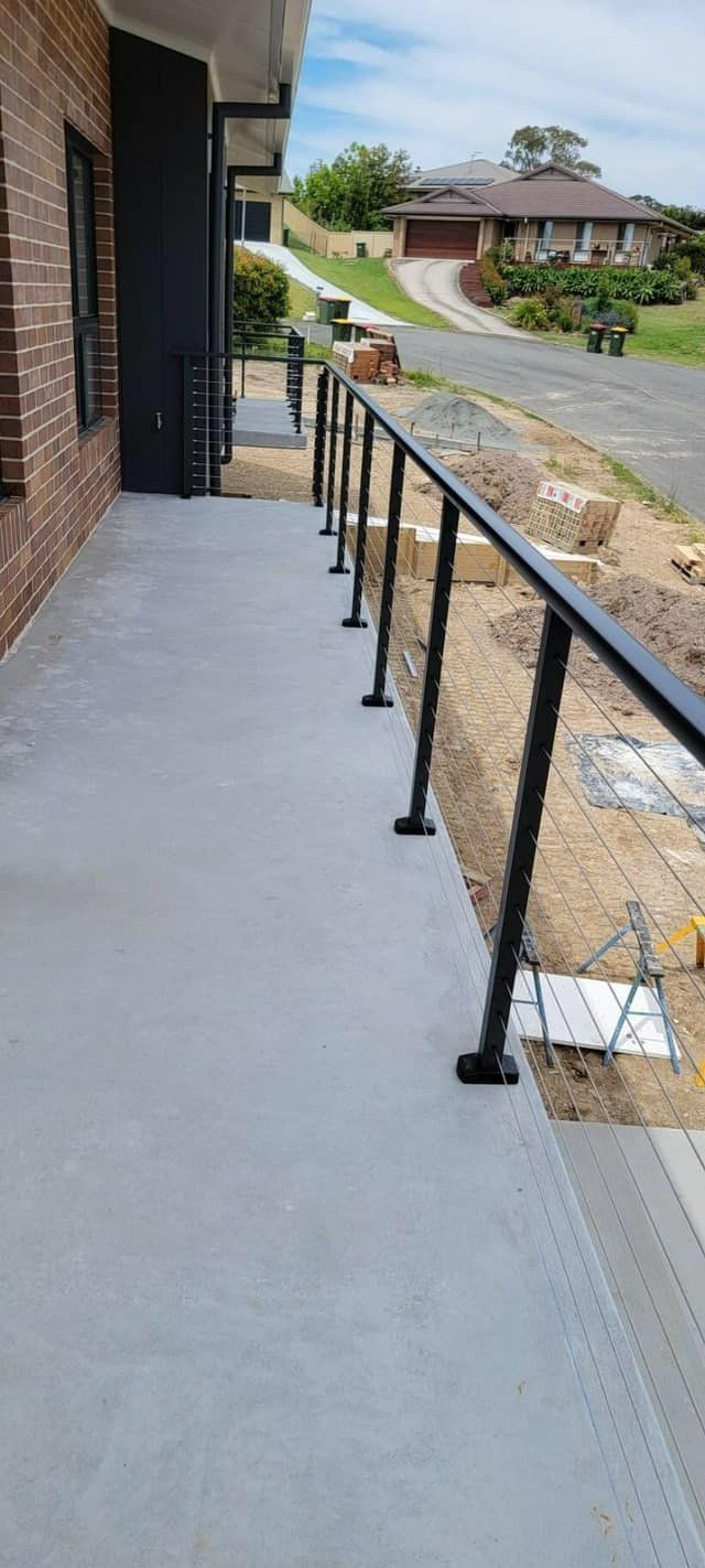 A Concrete Walkway with A Black Railing and A Brick Building — Oz-Craft in Taree, NSW