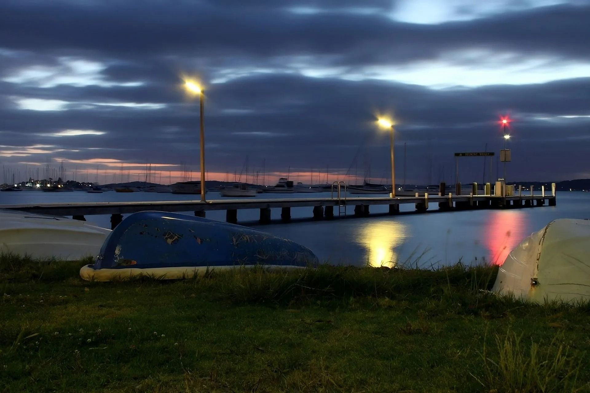 A Boat Sits on The Grass Near a Dock at Night — Oz-Craft in Port Macquarie, NSW