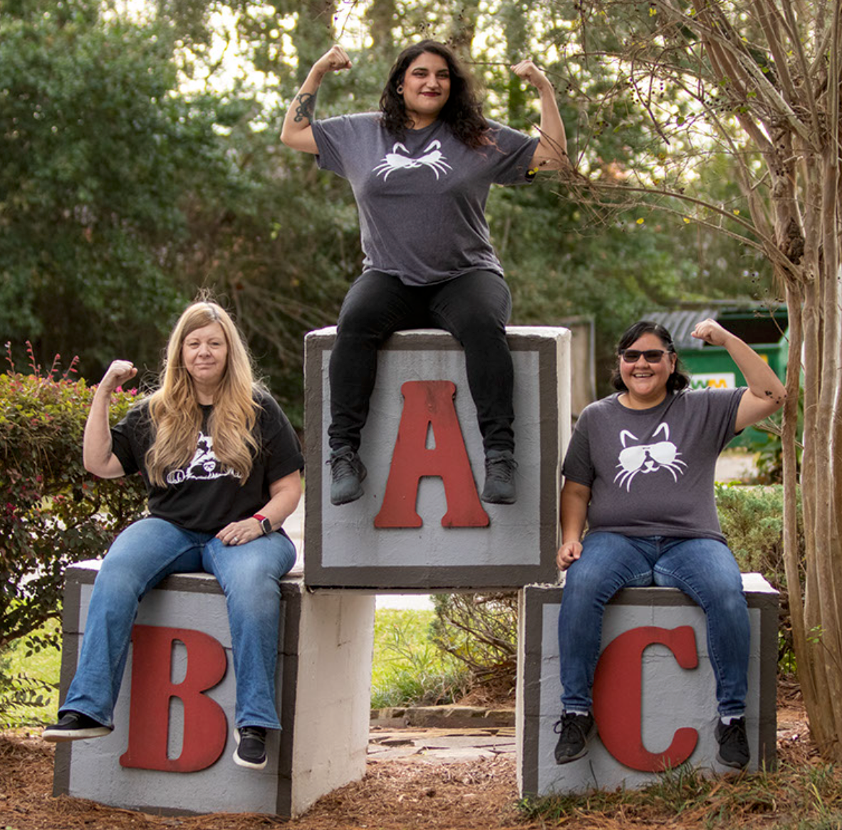 Three people are sitting on blocks with the letters a b and c on them