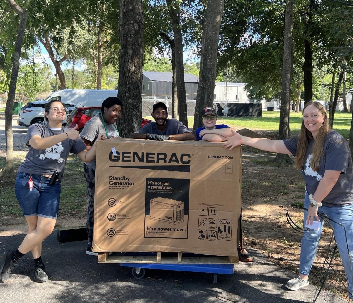 A group of people are standing around a generator box.