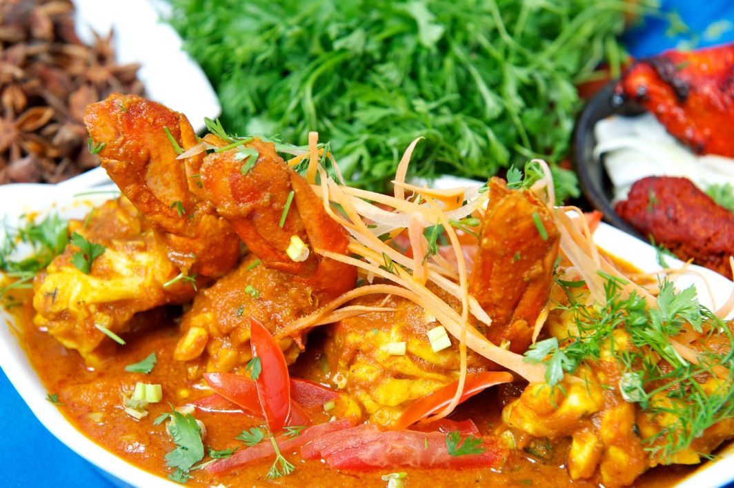 A close up of a plate of food with chicken and vegetables on a table.