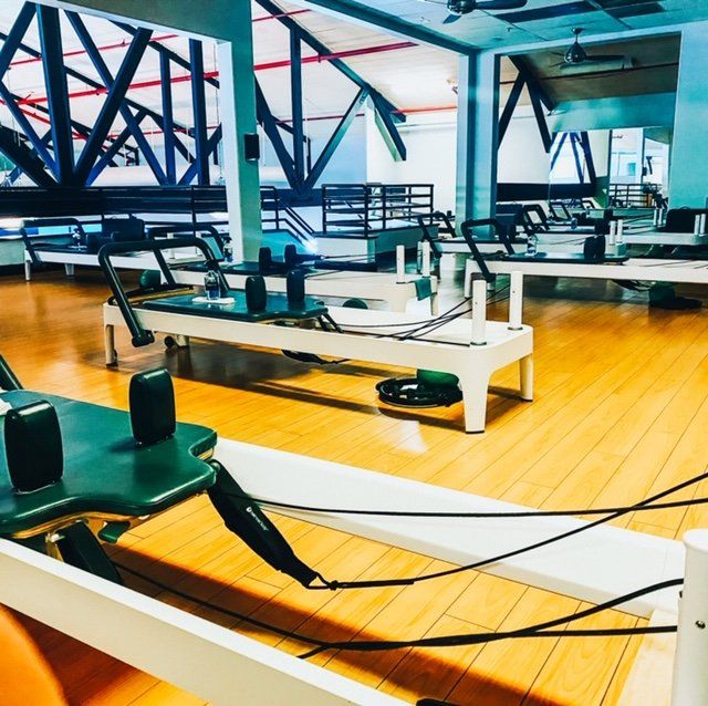 a gym with a lot of pilates machines on the floor